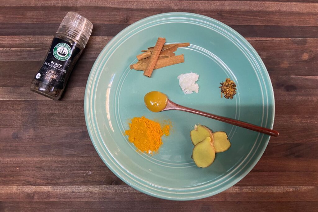 Spices for spiced milk recipe on green plate on wooden table
