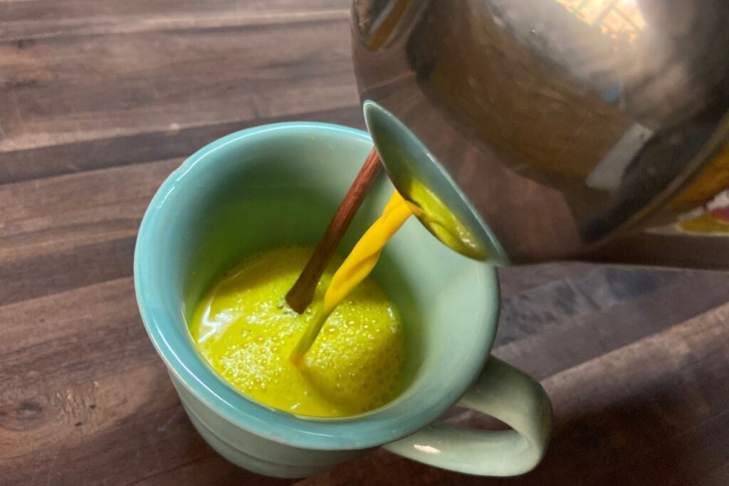 spiced milk being poured into green cup